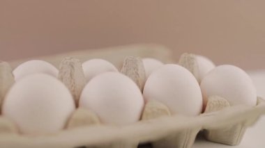 Beyaz arka planda karton tepside taze çiğ tavuk yumurtası.