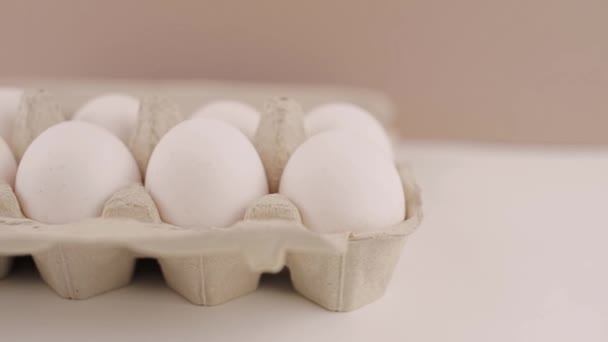 白い背景の段ボールのトレーの中の新鮮な生の鶏の卵 — ストック動画