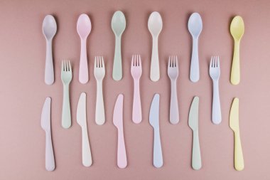 Farklı renklerde plastik çatal bıçak seti mutfak masasında çatal bıçak ve çevre dostu plastik.