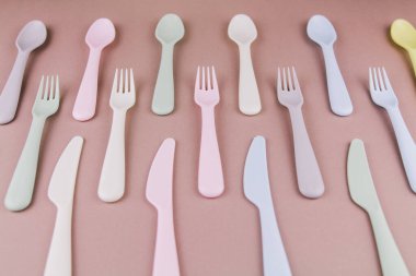 Farklı renklerde plastik çatal bıçak seti mutfak masasında çatal bıçak ve çevre dostu plastik.
