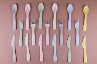 Farklı renklerde plastik çatal bıçak seti mutfak masasında çatal bıçak ve çevre dostu plastik.