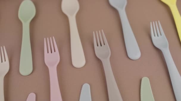 台所のテーブルの上に異なる色のスプーンフォークナイフでプラスチック再利用可能な刃物のセット — ストック動画