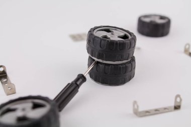 Beyaz arka planda fındıkları, vidaları ve tekerlekleri olan bir çocuk demir üreticisi.