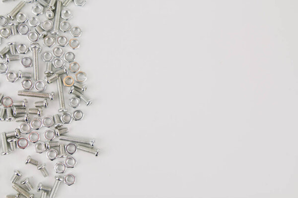железные винты и гайки на белом фоне для ремонта и строительства