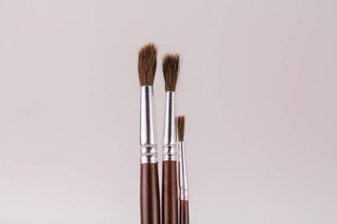 Bir bardak tutacağında beyaz bir arka planda boyamak için ahşap fırçalar