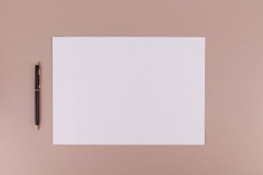 Ofisteki bir masanın üzerindeki beyaz bir kağıt parçasının yanında bir kalem ya da bir belge için