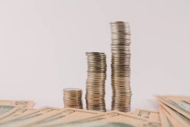 Beyaz arka planda dolar banknotlarıyla sütunlar halinde para sikkeleri