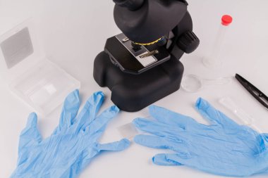 Laboratuvarda bir mikroskop ve masada tıbbi eldivenler.