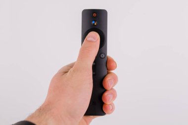 Beyaz arka planda bir adamın elindeki akıllı bir televizyondan modern bir uzaktan kumanda.