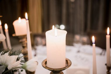 Lokantadaki masada beyaz mumlar yanıyor.