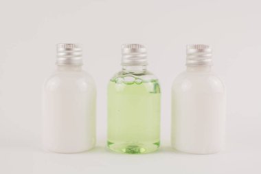 Beyaz arka planda krem, şampuan ve kozmetik içeren saydam kavanozlar.