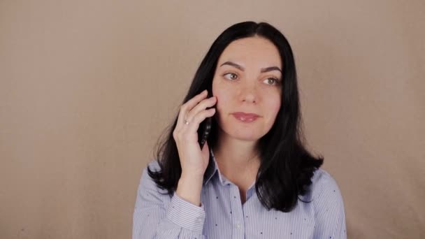 一个黑头发的女人 穿着衬衫 在手机后面说话 — 图库视频影像