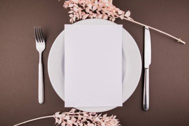 Masanın üzerinde çatal bıçak takımı ve dekoru olan beyaz bir tabak.