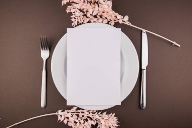 Masanın üzerinde çatal bıçak takımı ve dekoru olan beyaz bir tabak.