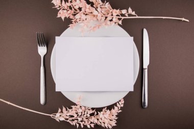 Masanın üzerinde çatal bıçak takımı ve dekoru olan beyaz bir tabak.