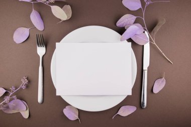 Masada çatal bıçak ve çiçek dekoru olan bir tabak.