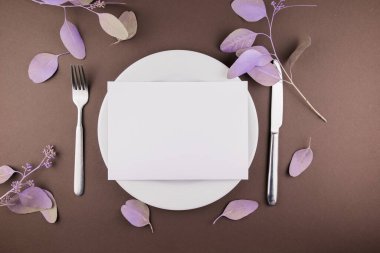 Masada çatal bıçak ve çiçek dekoru olan bir tabak.