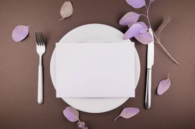 Masada çatal bıçak ve çiçek dekoru olan bir tabak.