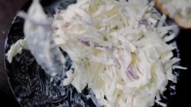 Lahanalı salata tabakta kaşıkla karıştırılır.