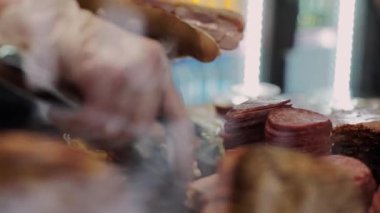 Bir adam kafede jambonlu sandviç yapıyor.