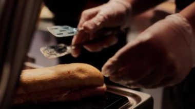 Adamın biri ızgaraya sandviç koyar.