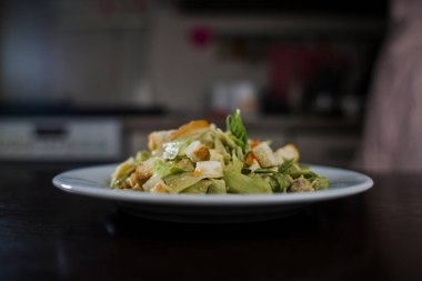 Mutfakta beyaz tabakta sezar salatası.