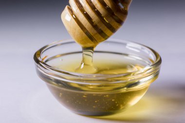 Taze altın bal, ahşap bir bal kaşığından güzelce dökülür.