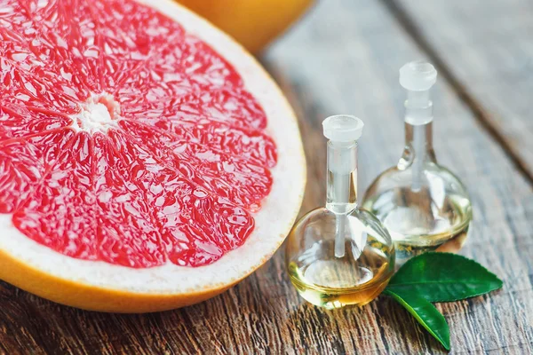 Essential oil in glass bottle with grapefruit. — Stock Photo, Image