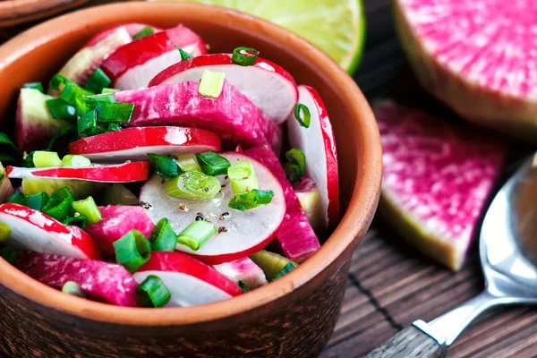 Fresh radish salad with assorted seasonal vegetables and green onions in brown bowl on wooden table. Organic food closeup. Selective Focus. — Stockfoto
