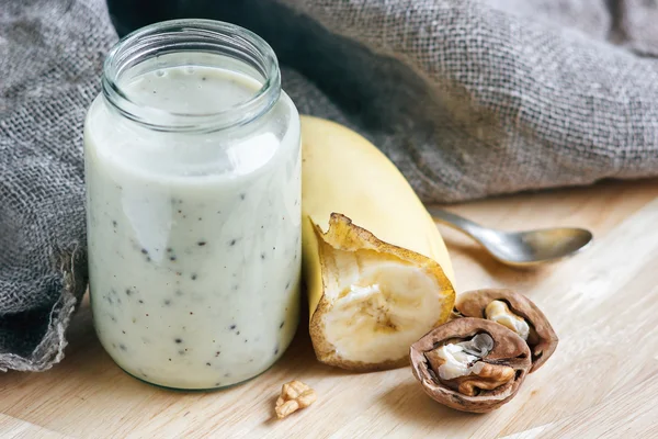 Yogur con plátano y nueces en un frasco de vidrio para una comida saludable por la mañana, enfoque selectivo — Foto de Stock