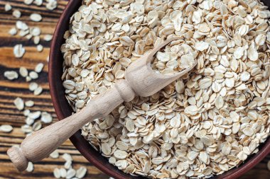 Gıda. Masada yulaf ezmesi. Eski ahşap masa üzerinde kahverengi kase kuru haddelenmiş yulaf gevreği yulaf ezmesi.