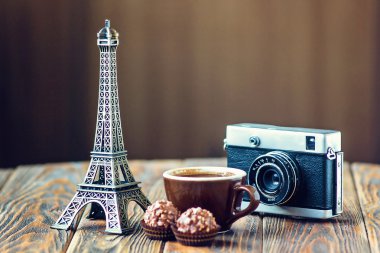 Love Paris! Rose, vintage camera, Eiffel tower, coffee cup and chocolate on wooden background. St Valentine's Day concept. Nostalgic holidays background