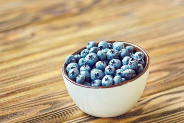 Beyaz kasede taze topüzümlü yaban mersini. Rustik masada sulu ve taze yaban mersini. Ahşap Arka Plan üzerinde Bilberry. Yaban mersini antioksidan. Sağlıklı beslenme ve beslenme kavramı.