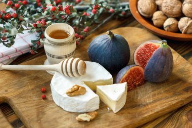Yumuşak olgun kremalı Fransız Camembert peyniri dilimlenmiş yuvarlak ahşap bir arka plan üzerinde taze sulu olgun kırmızı incir, bal ve ceviz ile servis