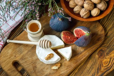 Yumuşak olgun kremalı Fransız Camembert peyniri dilimlenmiş yuvarlak ahşap bir arka plan üzerinde taze sulu olgun kırmızı incir, bal ve ceviz ile servis