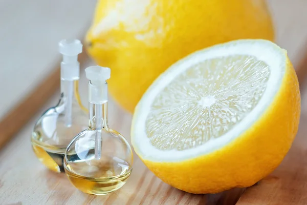 Ätherisches Aromaöl in Glasflasche mit frischen, saftigen Zitronenfrüchten auf Holzgrund. Schönheitsbehandlung. Wellness-Konzept. Selektiver Fokus. — Stockfoto