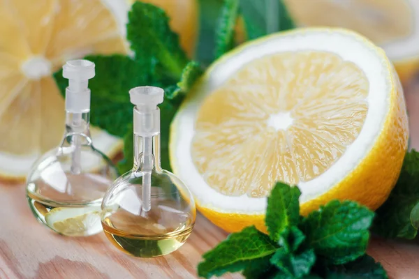 Ätherisches Öl in Glasflasche mit frischen, saftigen Zitronenfrüchten und grünen Minzblättern zur Schönheitsbehandlung. Wellness-Konzept. Selektiver Fokus. — Stockfoto