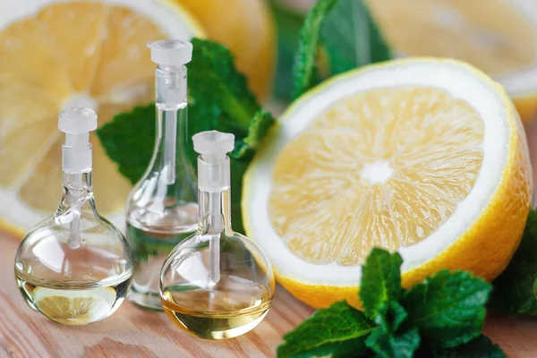 Óleo essencial em garrafa de vidro com frutas frescas e suculentas de limão e folhas verdes de tratamento de beleza de hortelã. Conceito de spa. Foco seletivo . — Fotografia de Stock