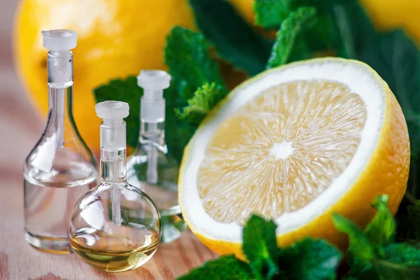 Ätherisches Öl in Glasflasche mit frischen, saftigen Zitronenfrüchten und grünen Minzblättern zur Schönheitsbehandlung. Wellness-Konzept. Selektiver Fokus. — Stockfoto