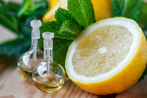 Aceite esencial en botella de vidrio con fruta fresca y jugosa de limón y hojas verdes de tratamiento de belleza de menta. Concepto Spa. Enfoque selectivo . —  Fotos de Stock