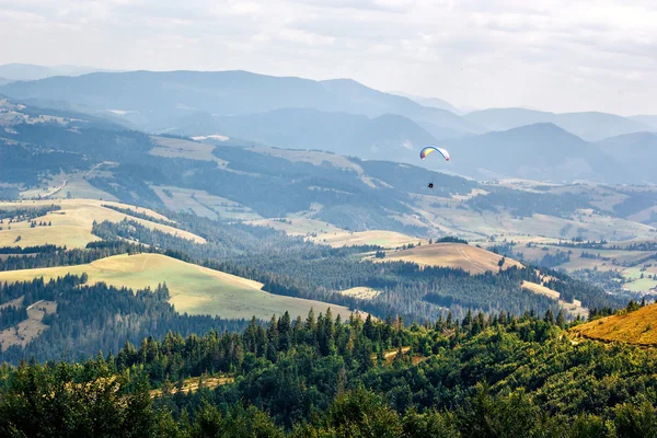 Paraglider flying against beautiful mountains landscape. Carpathian, Ukraine.