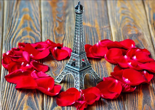 Patung menara Eiffel dan kelopak mawar merah berbentuk hati pada latar belakang kayu. Perjalanan, konsep cinta. Hari St Valentine — Stok Foto