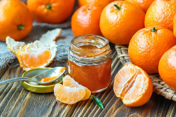 Mermelada de mandarina casera en frasco de vidrio con fruta alrededor en una mesa de madera —  Fotos de Stock