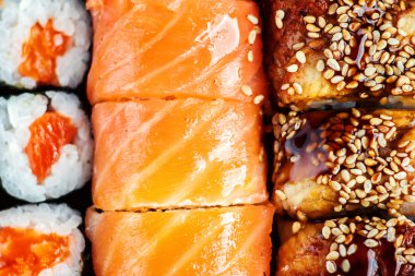 Suşi Seti sashimi ve suşi rulo koyu plaka üzerinde servis edilir. Koyu arka plan üzerinde Japon gıda görüntüsü. Üstte görüntü.