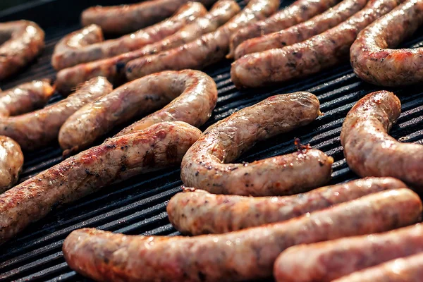 Churrasco com salsichas de fogo na grelha. Salsichas suculentas vermelhas assadas na fileira. Salsicha saborosa se preparando em uma churrasqueira sobre carvão vegetal no exterior . — Fotografia de Stock