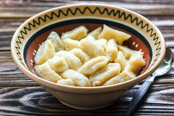 Ukrainian traditional lazy dumplings with cottage cheese. Ukrainian Cuisine. Homemade vareniki in a bowl, delicious lunch. Healthy breakfast - health and diet concept on the wooden table, closeup.