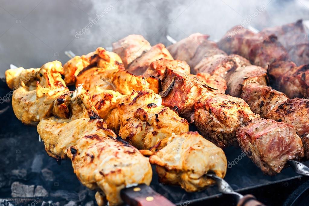 Marinated shashlik preparing on a barbecue grill over charcoal ...