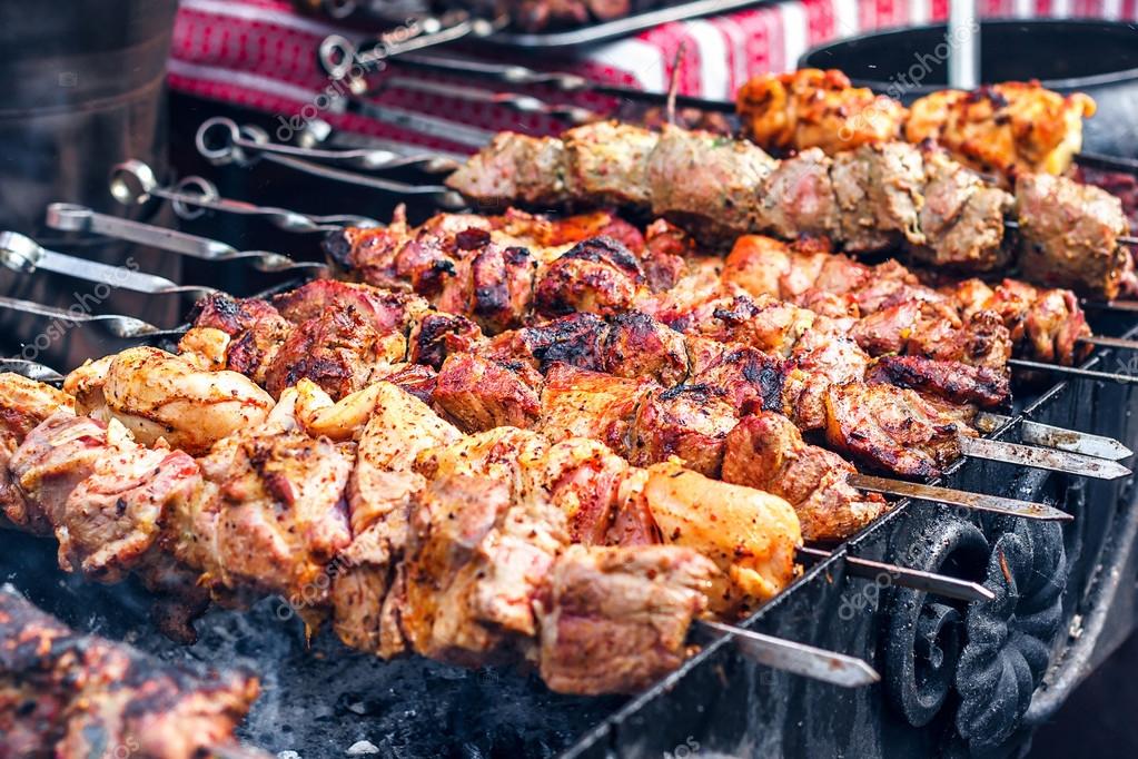 Marinated shashlik preparing on a barbecue grill over charcoal. Shashlik or Shish popular in Eastern Europe. (skewered meat) was originally made of lamb. Roast Kebabs On BBQ Grill. Stock