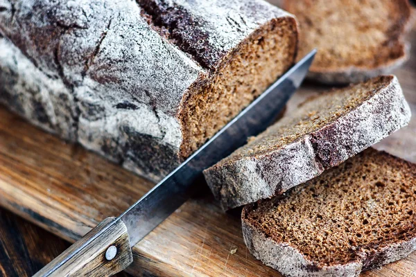 Нарезанный хлеб и нож. Буханка хлеба с первой половиной уже разрезана на ломтики . — стоковое фото