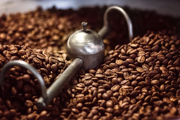 Miscelazione primo piano caffè torrefatto. Una serie di chicchi di caffè aromatici appena tostati si raffreddano dopo essere usciti da un torrefattore. Macchina moderna utilizzata per arrostire i fagioli . — Foto Stock